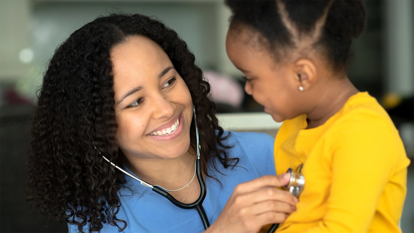nurse smiling using stethoscope on child