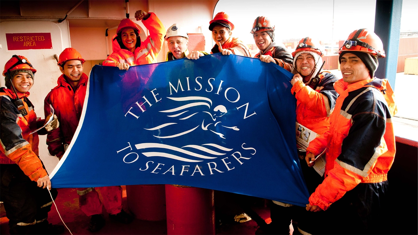 Mission to Seafarers members holding a flag with logo on