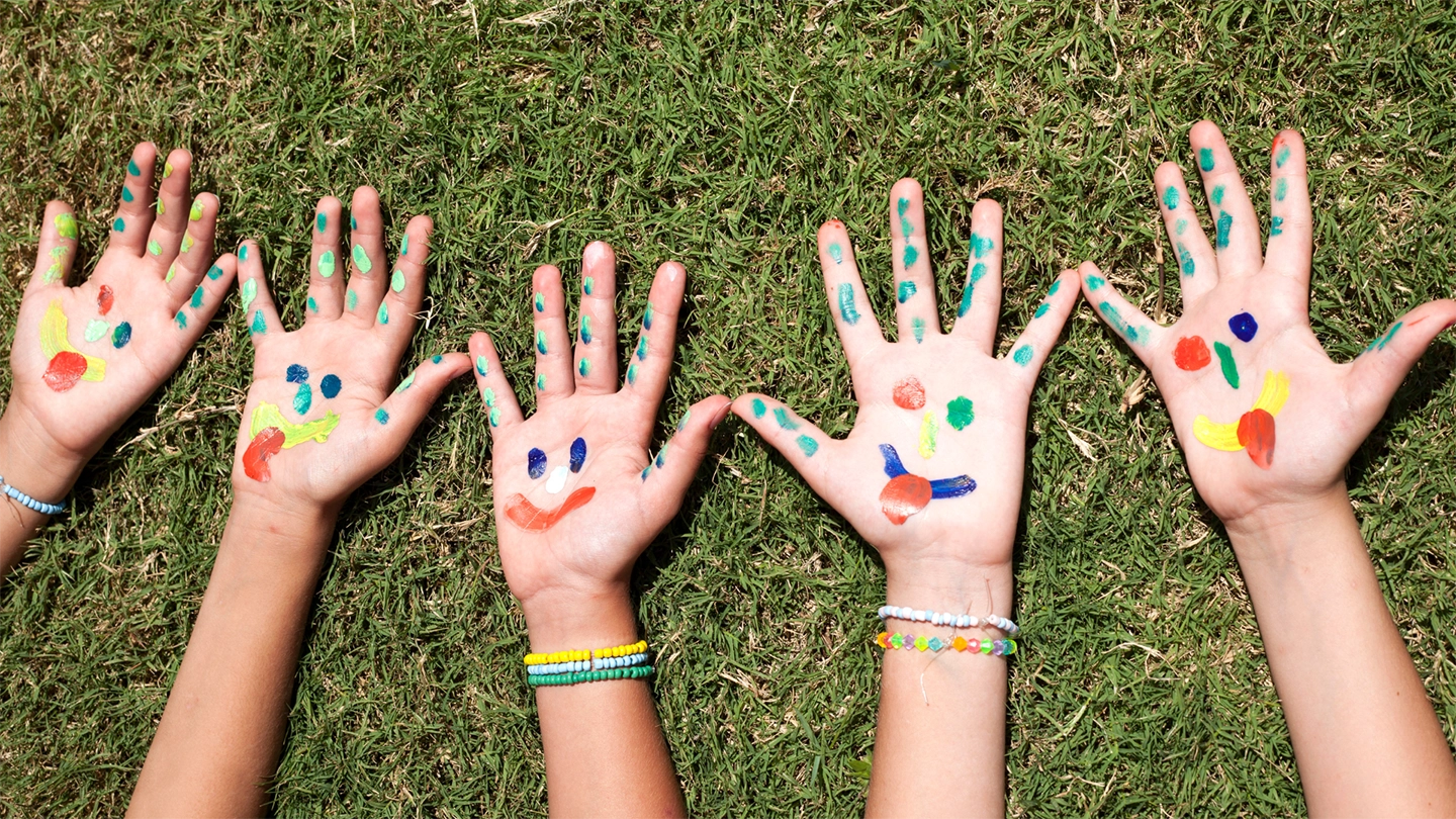 kids hands with smiley faces painted on