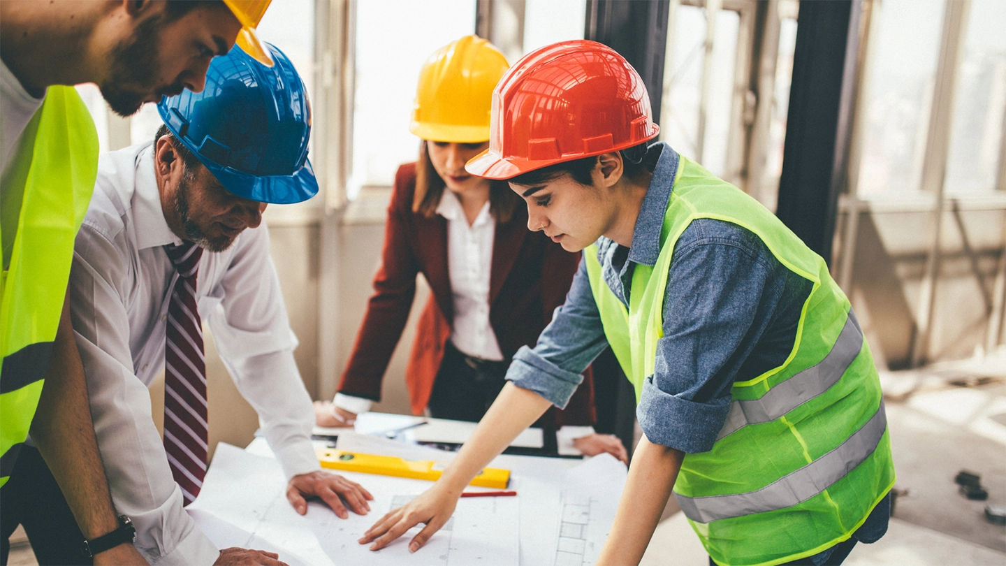 group of construction workers talking over blueprints