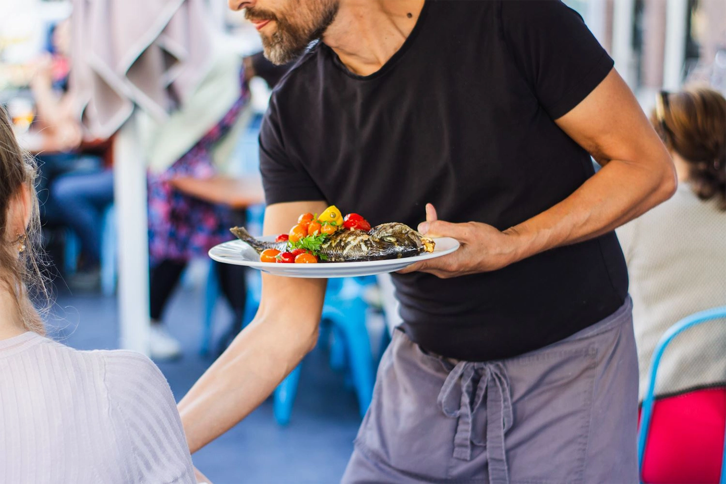 man serving a customer outside with fish on a plate